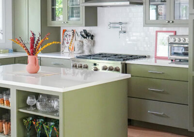 Sage green shaker kitchen cabinets with glass fronts and a matching island with open shelving and white quartz countertops