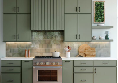 Sage green kitchen cabinets with slab and shaker fronts, quartz countertops, and a stainless gas range.