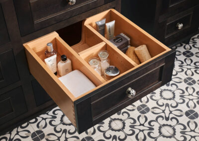 Bathroom cabinet with a drawer pulled out that has bath products organized in it.