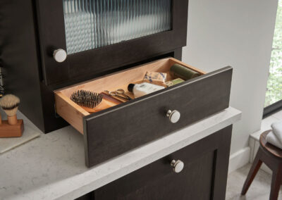 Bathroom vanity pull out drawer under cabinet containing beard care products.