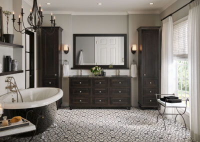 Dark brown bathroom cabinets with two tall shelving units in bright bathroom.
