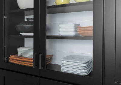 Dark wood built-in cabinet with multi-colored dishware on display.