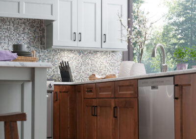 Kitchen with gray and brown cabinetry, white countertops, and built-in stainless steel appliances.