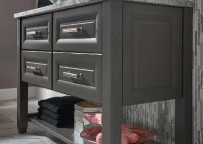 Gray bathroom vanity with marble countertop in a light colored bathroom.