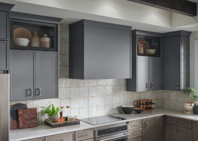 Kitchen with gray upper cabinets, white subway tile backsplash, open wood shelves, and black hardware.