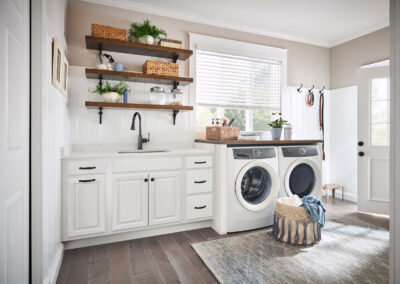 Laundry room with white built-in cabinetry, subway tile backsplash, and wood countertop.