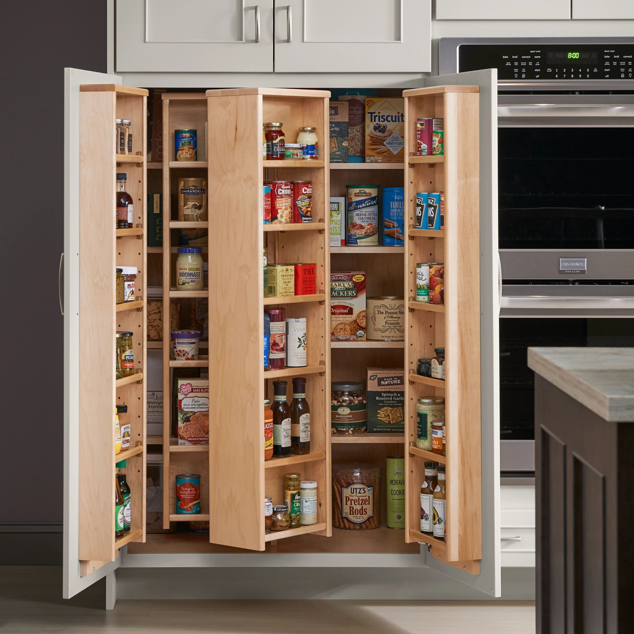 Pull-out trash bin cabinet with a plastic liner in a dark wood bathroom vanity with tiled flooring and patterned backsplash.